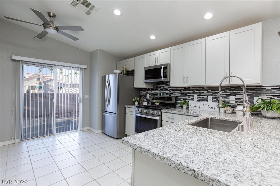 2254 Ramsgate Drive Henderson, NV 89074 - Photo 9 of 43 A well-appointed kitchen showcasing pristine white cabinetry and granite countertops, with sliding glass doors leading to outdoor living.