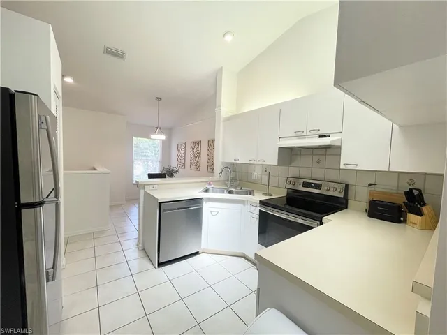 a kitchen with a sink a stove a refrigerator and white cabinets