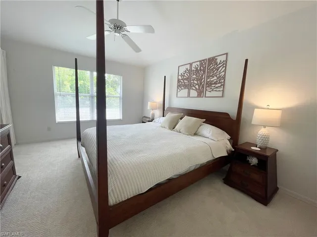a bedroom with a bed painting on wall and a large window