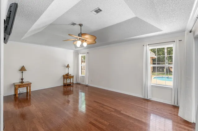an empty room with wooden floor and windows