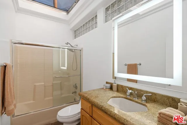 a bathroom with a granite countertop sink toilet a mirror and shower