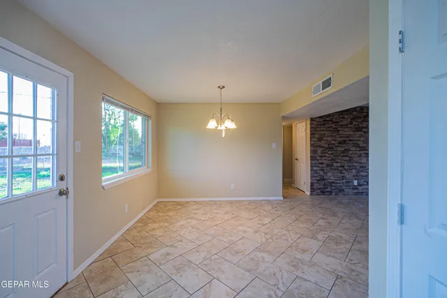 a view of an empty room with window and chandelier fan
