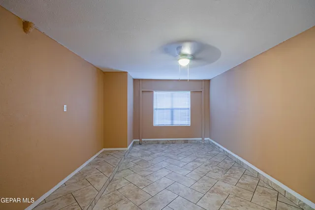 a view of an empty room with window and chandelier fan