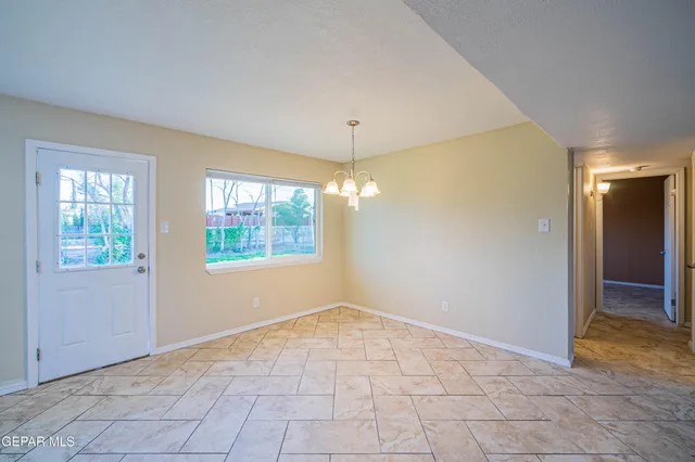 a view of an empty room with window and chandelier fan