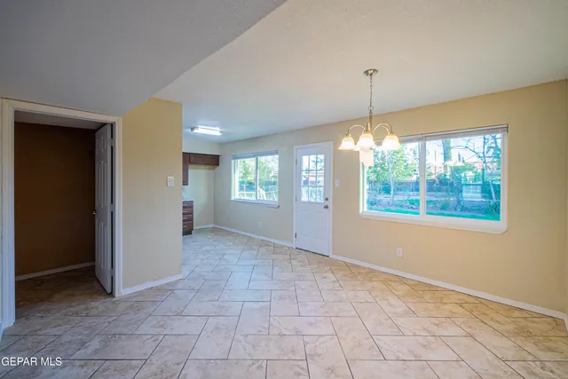 a view of an empty room with window and chandelier fan