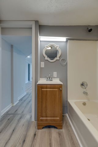 a bathroom with a tub a sink and wooden floor