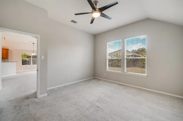 an empty room with chandelier fan and windows