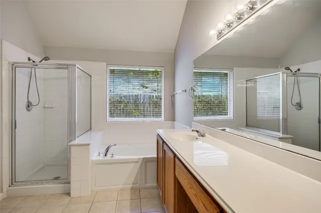 a bathroom with a tub sink shower and mirror