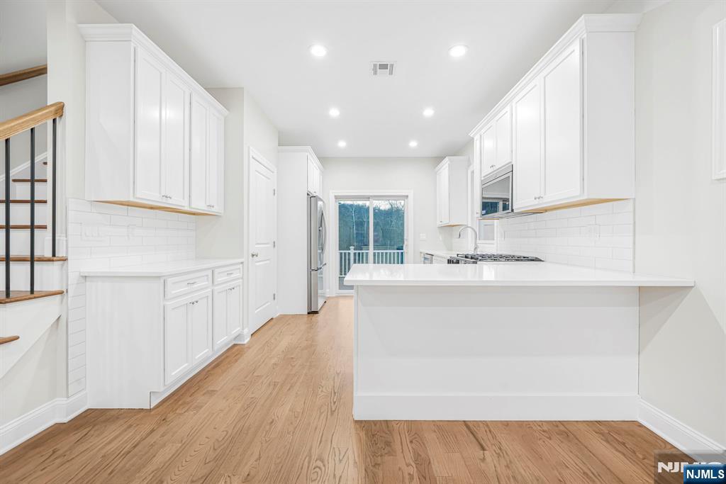 18 Birdie Lane Boonton, NJ 07005 - Photo 11 of 36 a large white kitchen with wooden floor and cabinets