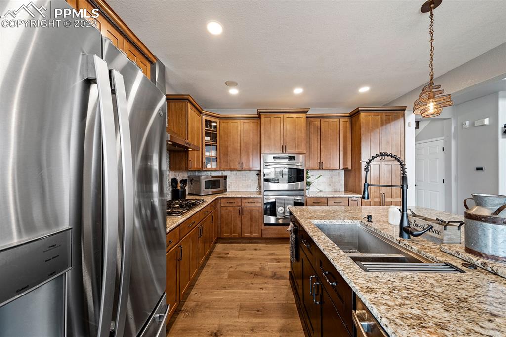 1465 Bowstring Road Monument, CO 80132 - Photo 17 of 49 a kitchen with stainless steel appliances granite countertop a sink refrigerator and cabinets