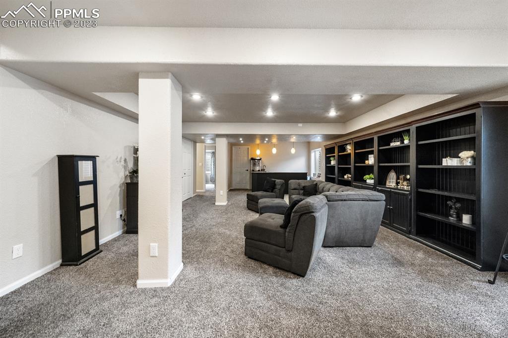 1465 Bowstring Road Monument, CO 80132 - Photo 40 of 49 a living room with furniture a walk in closet and a projector