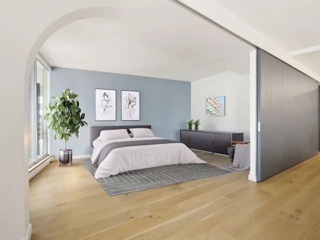 a spacious bedroom with a bed and a potted plant