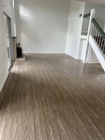 a view of an empty room with wooden floor and staircase