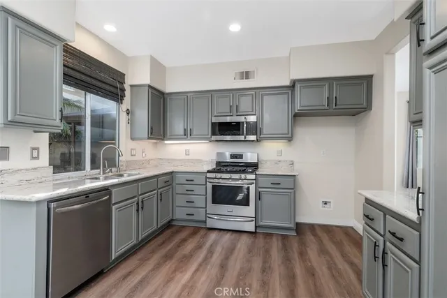a kitchen with stainless steel appliances granite countertop a stove top oven a sink and a refrigerator