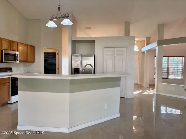 a kitchen with stainless steel appliances granite countertop a sink a stove top oven a refrigerator with kitchen island and chairs