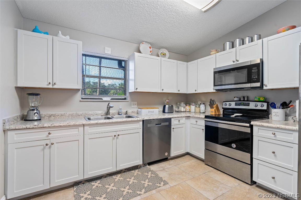 1109 Regent Street Edgewater, FL 32132 - Photo 8 of 27 a kitchen with granite countertop white cabinets sink and stainless steel appliances
