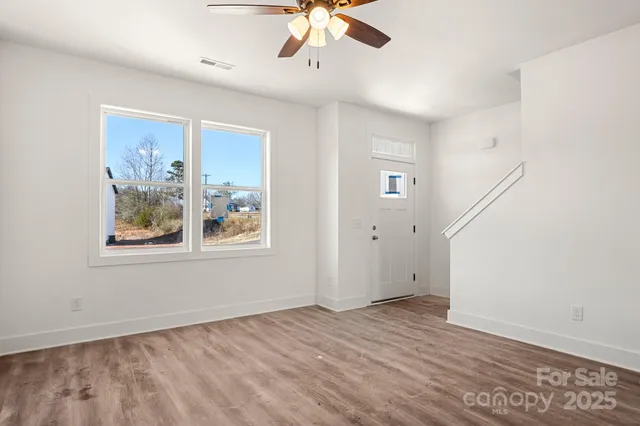 a view of an empty room with a window and wooden floor