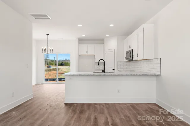 a kitchen with stainless steel appliances granite countertop a sink a stove a refrigerator and white cabinets with wooden floor