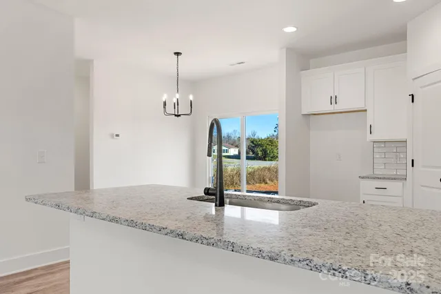 a view of a kitchen with kitchen island a sink wooden floor and glass windows
