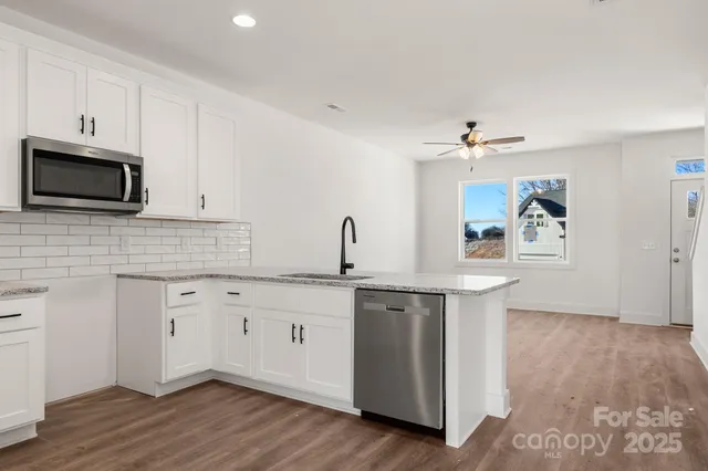 a kitchen with stainless steel appliances a sink cabinets and wooden floor