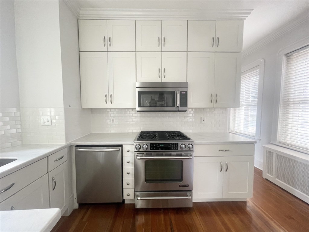 145 Charles Street, Unit 4 Boston, MA 02114 - Photo 13 of 24 a kitchen with white cabinets and stainless steel appliances