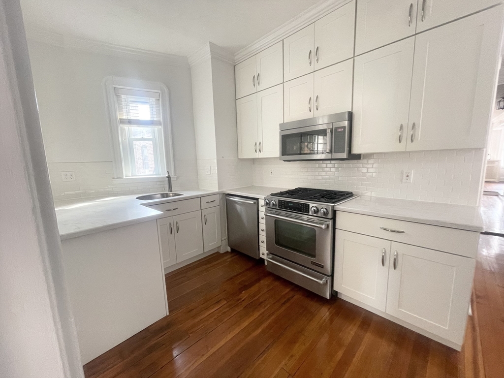 145 Charles Street, Unit 4 Boston, MA 02114 - Photo 14 of 24 a kitchen with stainless steel appliances white cabinets and a wooden floor