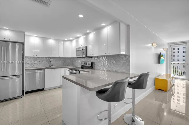 a kitchen with stainless steel appliances granite countertop a refrigerator a stove and a sink