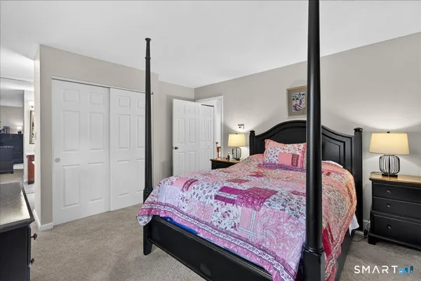 a bedroom with a bed a walk in closet and a mirror