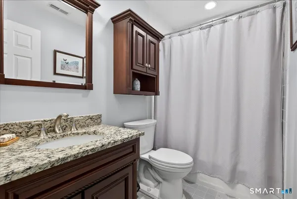 a bathroom with a granite countertop sink and a toilet