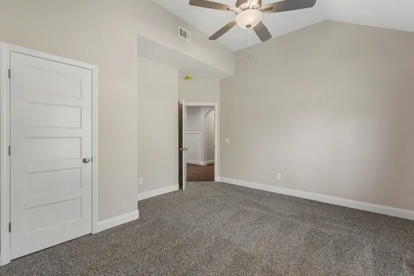 an empty room with a ceiling fan and carpet