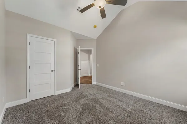 an empty room with a ceiling fan and carpet