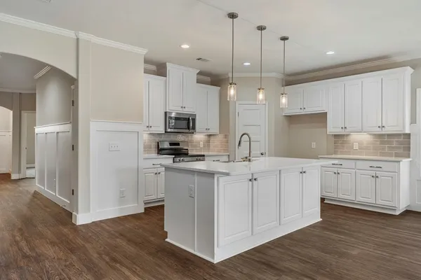 a kitchen with kitchen island granite countertop a sink cabinets and wooden floor