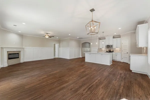 a view of a kitchen with kitchen island wooden floor stainless steel appliances and cabinets