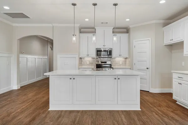 a large white kitchen with white cabinets and wooden floor