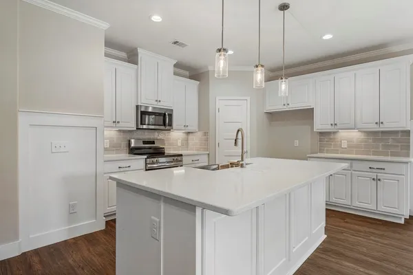 a kitchen with kitchen island granite countertop a sink cabinets and stainless steel appliances