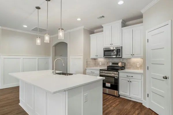 a kitchen with stainless steel appliances a stove top oven a sink a refrigerator and white cabinets