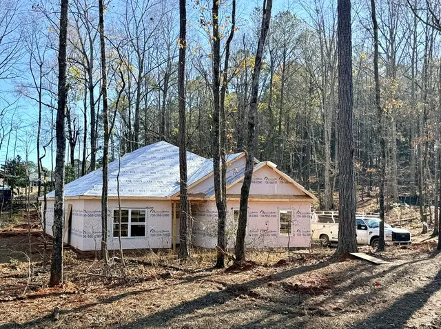 a backyard of a house with large trees and wooden fence