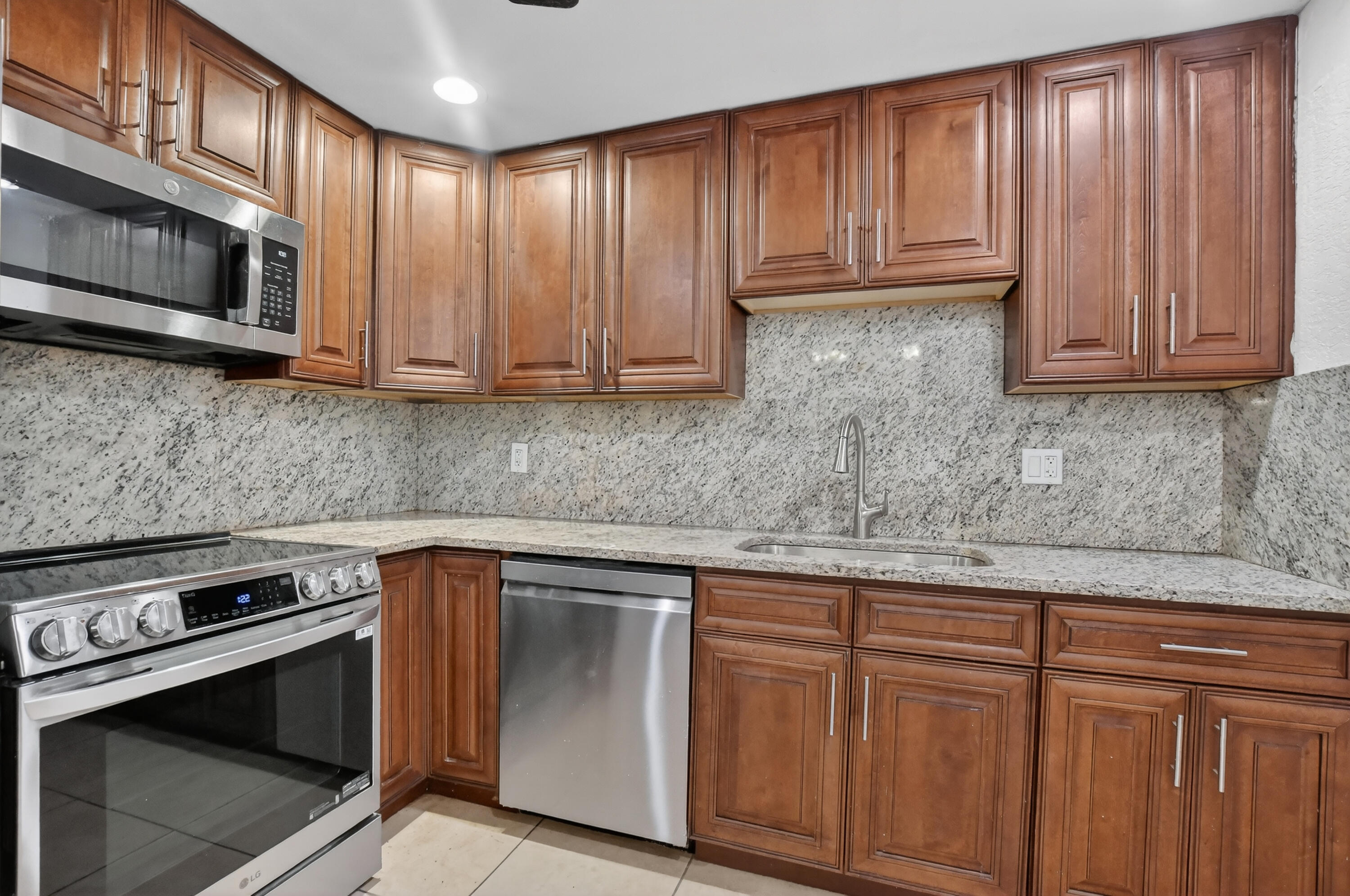 636 Northwest 13th Street, Unit 110 Boca Raton, FL 33486 - Photo 19 of 35 a kitchen with granite countertop wooden cabinets and stainless steel appliances