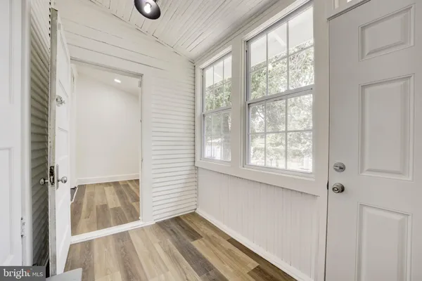 an entryway of a room with wooden floor and windows