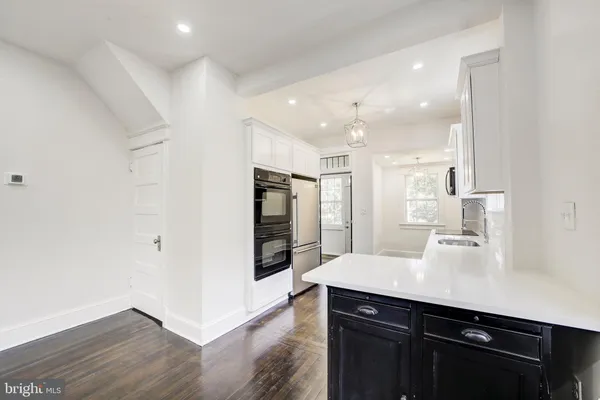 a kitchen with stainless steel appliances a sink cabinets and wooden floor