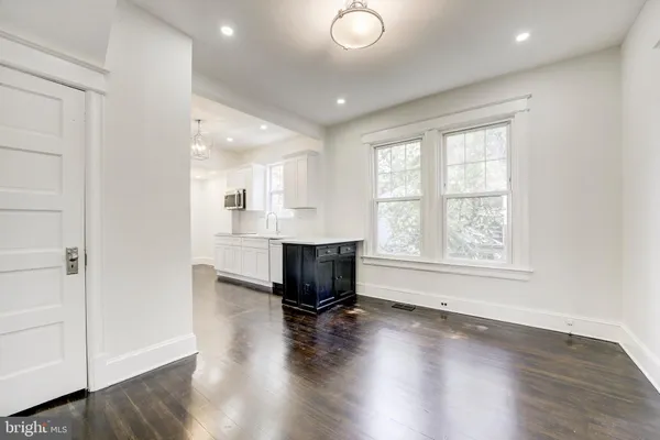 an empty room with wooden floor cabinet and windows