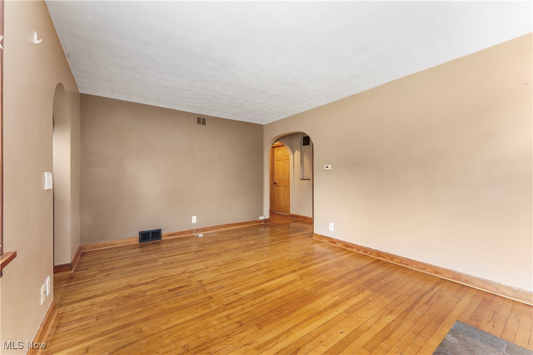 Empty room with arched walkways and light wood-style floors