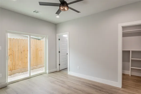 an empty room with wooden floor closet and windows