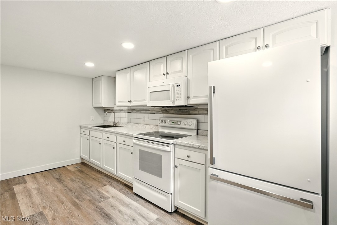 2844 Kent Road Stow, OH 44224 - Photo 36 of 47 Kitchen featuring white appliances, white cabinets, light wood finished floors, light countertops, and backsplash