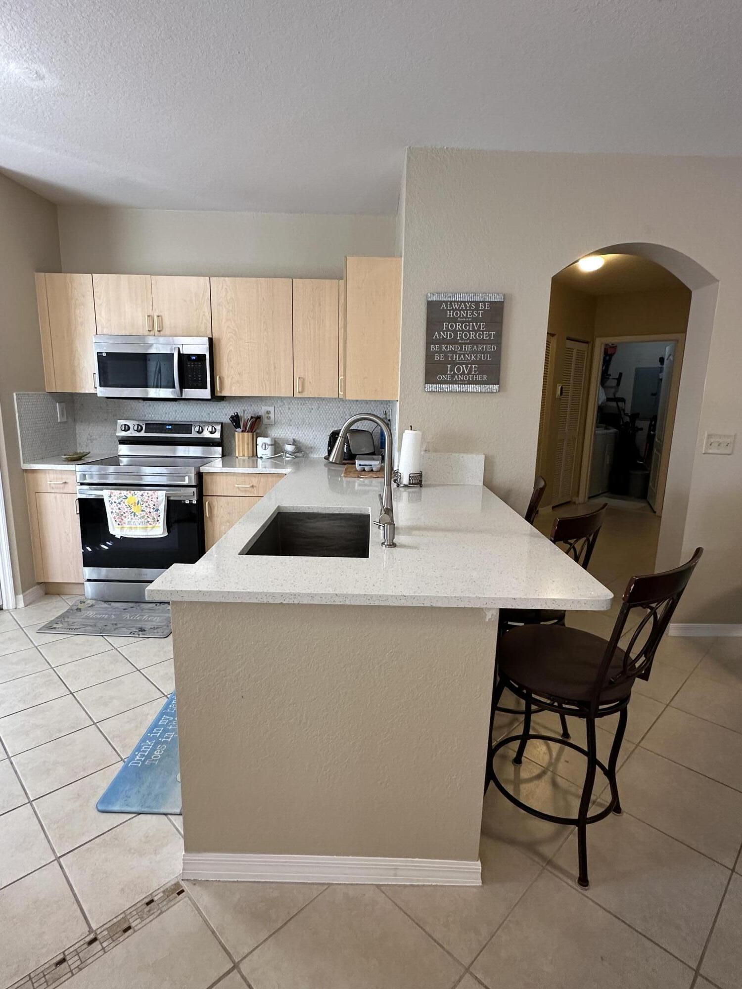 112 Southwest Peacock Boulevard, Unit 7202 Port St. Lucie, FL 34986 - Photo 4 of 11 a kitchen with a sink a counter top space and appliances