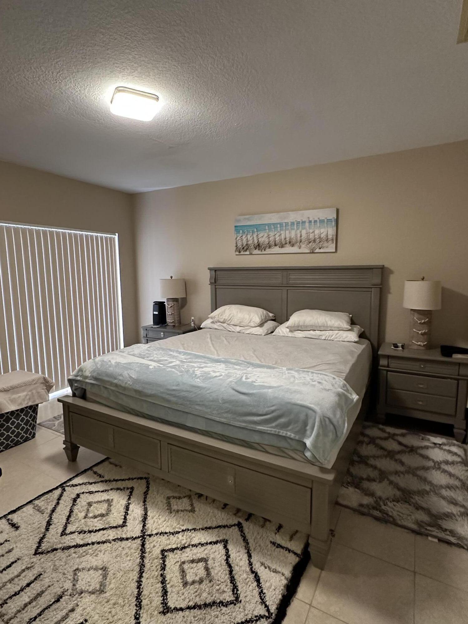 112 Southwest Peacock Boulevard, Unit 7202 Port St. Lucie, FL 34986 - Photo 7 of 11 a bedroom with a bed and a night stand