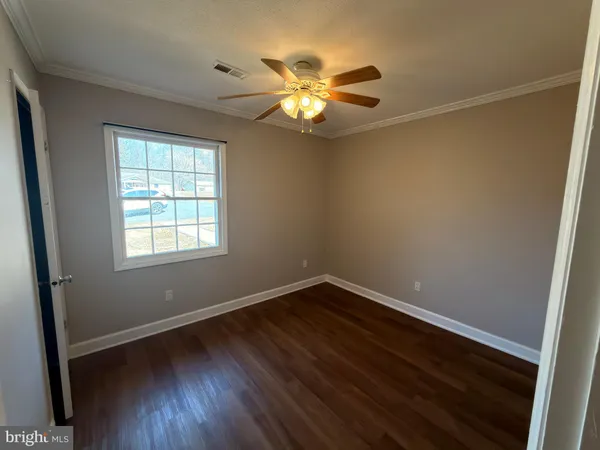 a view of wooden floor and a chandelier fan in a room