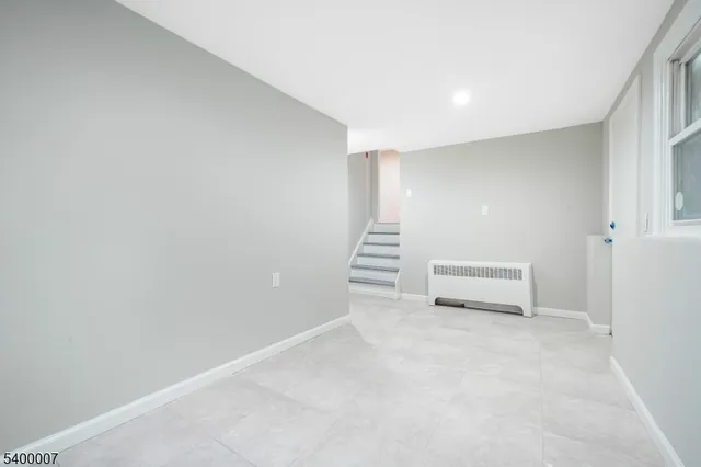 a view of an empty room with stairs and a window