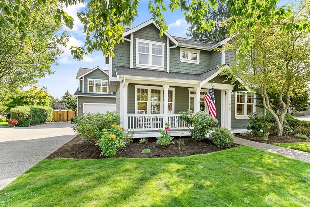 a view of a house with a small yard plants and large trees