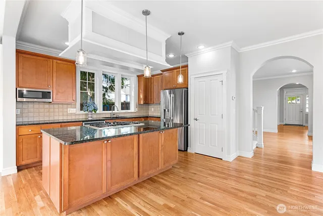 a large kitchen with stainless steel appliances granite countertop a sink and a wooden floor